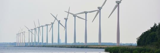 Een rij windturbines langs het water