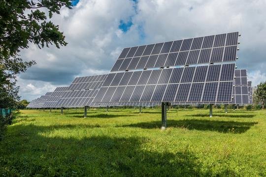 Zonnepanelen in een grasveld onder een blauwe lucht